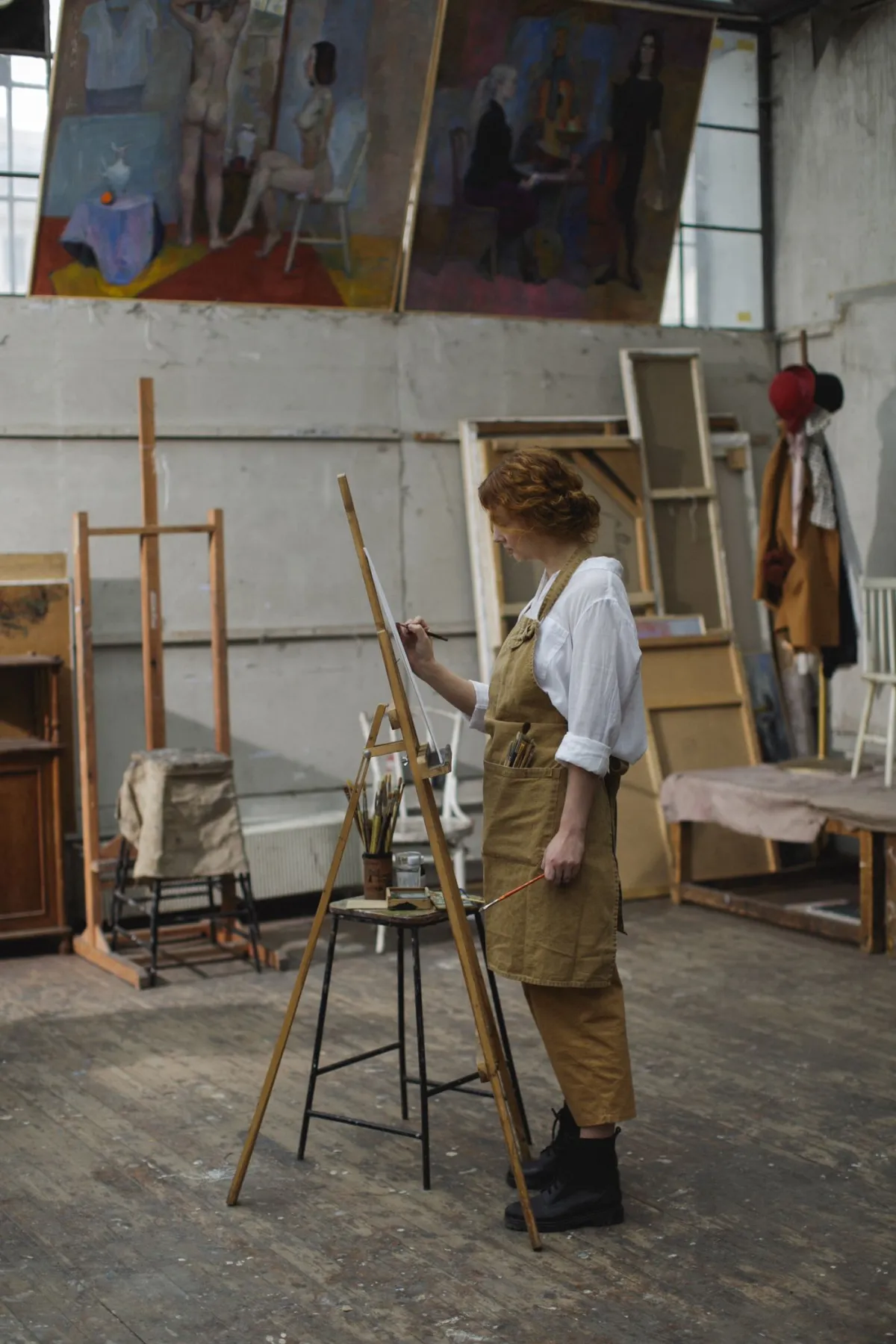 Kuenstlerin malt ein grossformatiges Bild an der Staffelei im Atelier